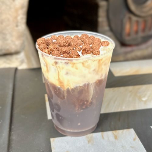 A Cold Brew Black Caf topped with sweet cream cheese topping and chocolate puffs