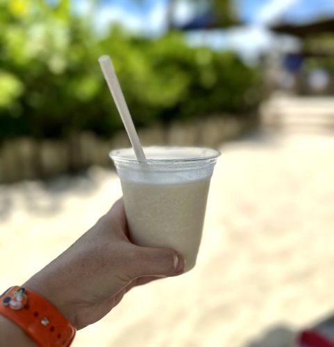 A piña colada in a plastic cup with a straw